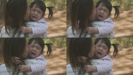 消极情绪亚洲母亲抱着哭泣的女婴在花园高清在线视频素材下载