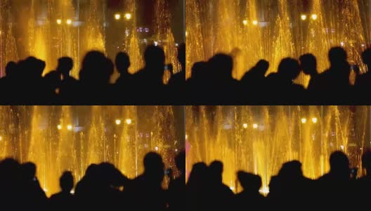 游客在晚上欣赏灯光喷泉，前景是剪影高清在线视频素材下载