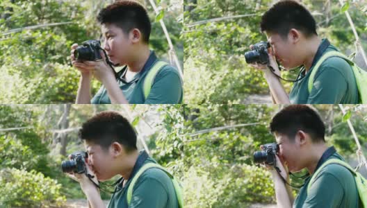 亚洲男孩学习使用相机如何拍摄以自然为背景，冒险的概念。高清在线视频素材下载