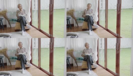 早上，退休的灰白头发的亚洲人爷爷坐在客厅看书，在家中自我隔离隔离。隔离或封锁期间在家活动的生活方式。高清在线视频素材下载