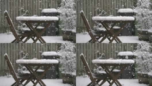 英国的一个花园正在下雪，花园里有家具和有轮子的垃圾桶高清在线视频素材下载