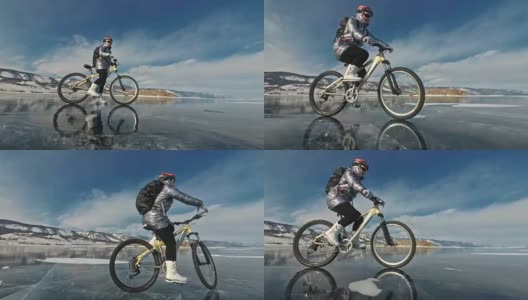 一个女人在冰上骑自行车。这个女孩穿着银色的羽绒服，背着自行车背包，戴着头盔。结冰的贝加尔湖的冰。自行车的轮胎上覆盖着特殊的尖钉。高清在线视频素材下载