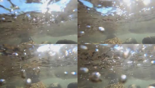浅河底部的石头，气泡和快速强劲的水流水面的特写高清在线视频素材下载