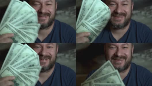 一个满脸胡须的心满意足的男人手里拿着美元。很多钱，意想不到的财富，中彩票，成功的概念。高清在线视频素材下载