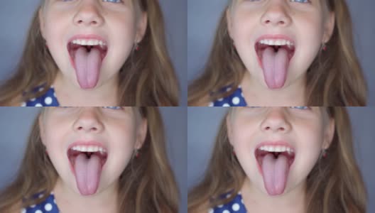 女孩张大嘴巴，伸出长长的舌头。孩子露出柔软的牙齿高清在线视频素材下载