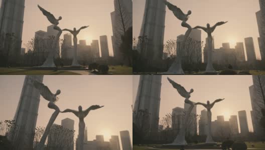 日落时分，上海陆家嘴中心绿地上的飞行双天使雕塑高清在线视频素材下载