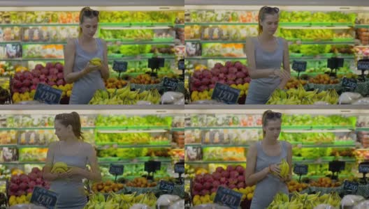一名年轻女子在超市水果部挑选一串香蕉高清在线视频素材下载