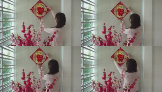 亚洲的中国妇女在中国新年前夕用“财运”春联装饰她的房子高清在线视频素材下载