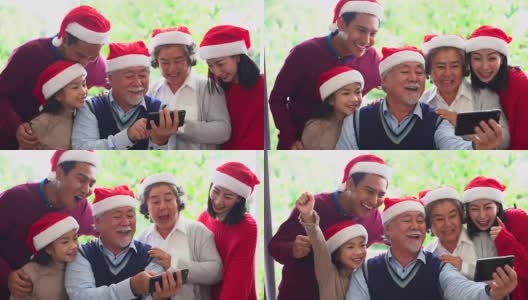 来自不同群体的亚洲人聚集在一起庆祝圣诞节。头发花白的爷爷奶奶，兄弟姐妹，儿子，女儿参加家庭宴会，坐在自制的午餐桌旁，在冷杉树下交谈。高清在线视频素材下载