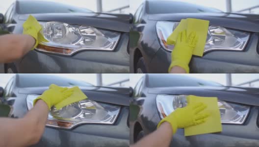 男子戴着黄色手套洗车灯的特写。汽车清洗的概念高清在线视频素材下载