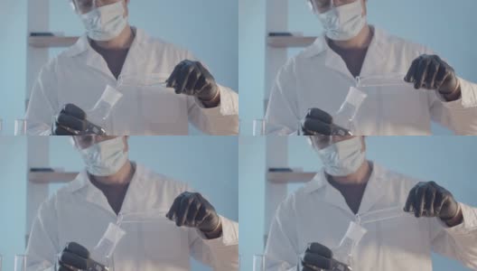 科学实验室的研究工作。一名医生穿着晨衣，戴着防护橡胶手套，戴着眼镜，近距离检查了烧瓶里的液体。高清在线视频素材下载