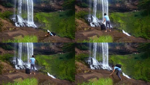 光着脚背着背包的人爬上瀑布旁的石头高清在线视频素材下载