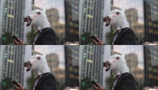 戴着独角兽面具的商人在城市里使用手机高清在线视频素材下载