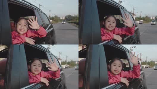 在去学校的路上，小女孩从车窗里伸出手，笑着，微笑着。亚洲小女孩微笑着，示意把车伸出来。孩子们在车里可以看到街景，放松心情。家庭在汽车的概念。高清在线视频素材下载