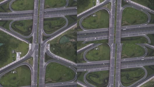 放大高度发达城市中现代三叶草形状的多级沥青交通枢纽的无人机航拍。高架道路和运动车辆的运动，高速公路之间的花坛。高清在线视频素材下载