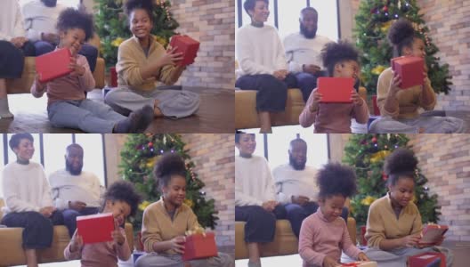 两个女儿在一起享受圣诞节或新年假期时，用礼物盒给她的妈妈和爸爸一个惊喜高清在线视频素材下载