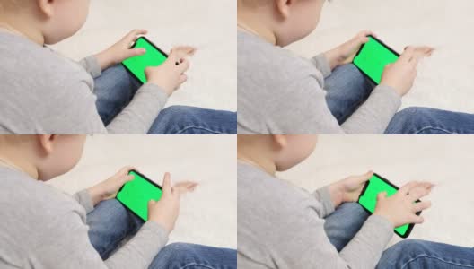 学龄前的孩子在家里用手机玩电子游戏。孩子们手里拿着智能手机的绿屏，技术一代的概念。关注chromakey高清在线视频素材下载