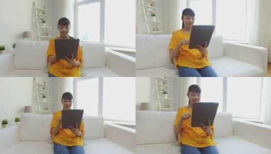 快乐的年轻亚洲女人在家里有平板电脑高清在线视频素材下载