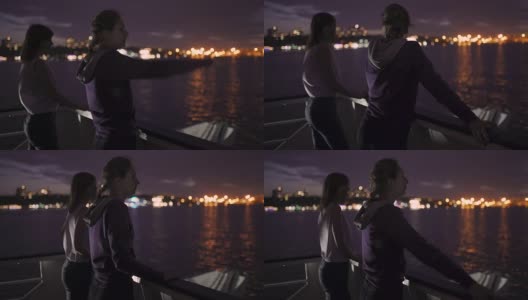 两个迷人的年轻女人的剪影在夜里在船上旅行。船上的闺蜜高清在线视频素材下载
