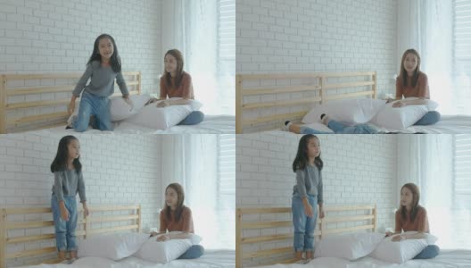 女孩和妈妈在床上用枕头玩游戏打架高清在线视频素材下载