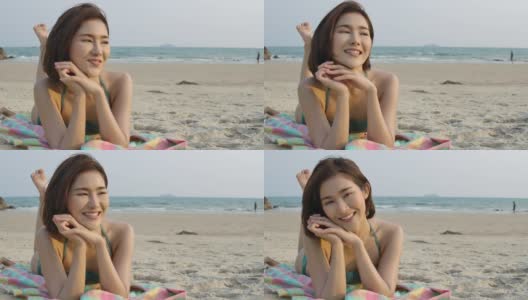 亚洲女孩穿着比基尼躺在沙滩上看镜头的肖像。美丽的亚洲女孩在暑假。庆祝和放松的概念。高清在线视频素材下载
