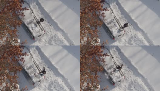 一个成年人在一场暴风雪后清理他的车。鸟瞰图正上方无人机视频。高清在线视频素材下载
