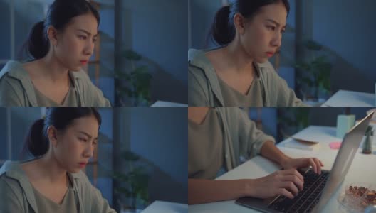年轻的亚洲自由职业女性使用笔记本电脑在家里的客厅晚上。高清在线视频素材下载