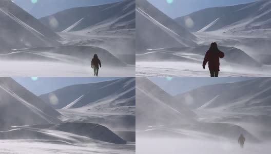 一个孤独的旅行者正穿过暴风雪，背景是雪山。高清在线视频素材下载
