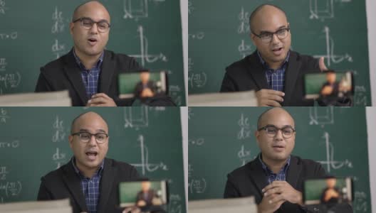 印度年轻教师男子坐着用智能手机进行在线视频会议直播。亚洲数学教师在线授课，供学生在线学习。高清在线视频素材下载