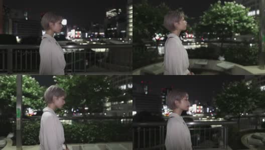 一名年轻女子在夜晚走在城市人行道上高清在线视频素材下载