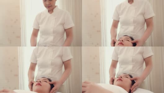 亚洲妇女在美容沙龙健康水疗按摩按摩的按摩师正在给女人面部按摩躺在床上高清在线视频素材下载