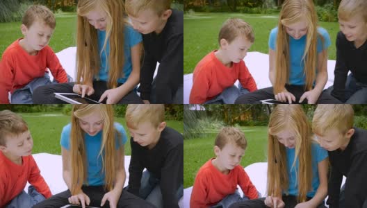 三个年幼的孩子完全沉浸在他们共享的平板电脑上——慢动作高清在线视频素材下载