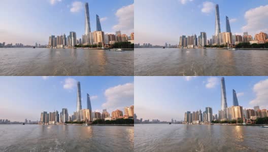 从轮渡、摩天大楼和地标建筑上看上海天际线，以蓝天为背景，黄浦江上的船只航行，江面上的船尾，水沫的痕迹，4K，慢镜头。高清在线视频素材下载