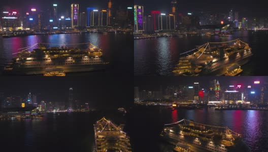 香港航拍v28低空飞过维多利亚港，周围是一艘小型游船，夜晚的城市风光一览无余。高清在线视频素材下载