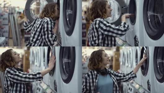 一个穿着格子衬衫的年轻女人正在家电商店里挑选洗衣机。打开门往里看。侧视图高清在线视频素材下载