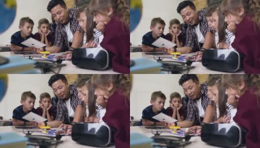 一组六名小学生，老师在课堂上使用数字平板电脑启动电子构造器风扇高清在线视频素材下载