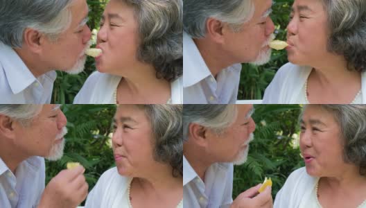 快乐的亚洲老年夫妇微笑着健康的橘子水果，老年男女退休后有一个幸福的生活，人们的生活理念。高清在线视频素材下载