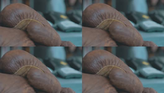在模糊的背景上旧的棕色皮革拳击手套的特写。视频。运动概念和运动器材高清在线视频素材下载