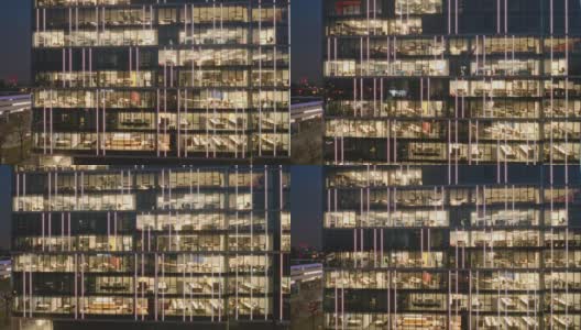 俯瞰摩天大楼的办公室和工作到很晚的人，办公室的窗户被照亮在商业中心大楼的立面上。高清在线视频素材下载
