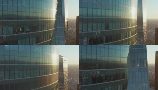 上升的镜头沿着窗户和玻璃幕墙的办公大楼反映在城市的建筑和日落。屋顶上挂着西班牙国旗高清在线视频素材下载
