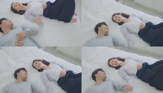 亚洲漂亮的快乐的年轻夫妇跳在床上休息在卧室。美丽的新婚男女穿着睡衣在清晨醒来和一起入睡后感到幸福和放松高清在线视频素材下载