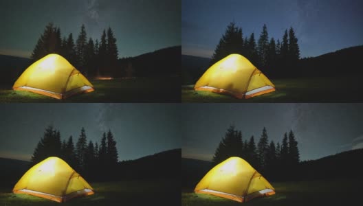 夜晚的星空下，明亮的帐篷在黑暗的山上闪闪发光。积极的生活方式和徒步旅行的理念高清在线视频素材下载