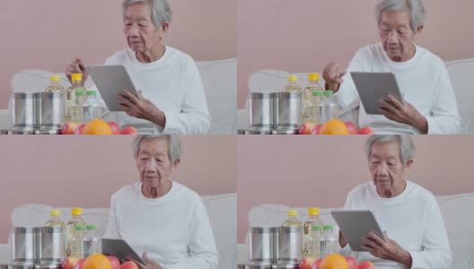 65岁以上的亚洲老年妇女使用科技平板电脑，在日常生活中轻松和自信地查看网上购物。技术，社会联系，网上购物，老年人购物，退休，技术精明的老年人高清在线视频素材下载