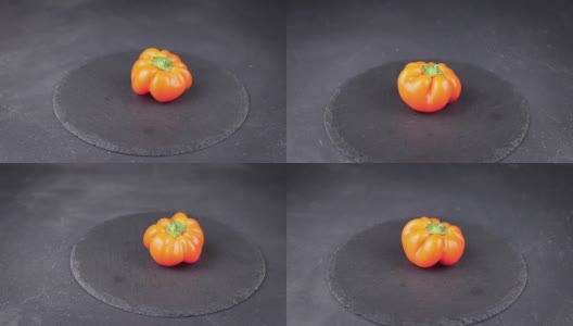 橙色灯笼椒在黑色圆形石头背景上旋转。多色蔬菜收获概念高清在线视频素材下载