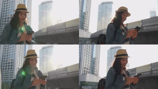 一位年轻美丽的亚洲女子使用手机，发短信，愉快地在城市中旅行。看着交通高峰时段的交通和空中列车的背景。高清在线视频素材下载
