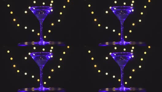 杯中的亮蓝色鸡尾酒，在昏暗的背景和模糊的光线下旋转。高清在线视频素材下载