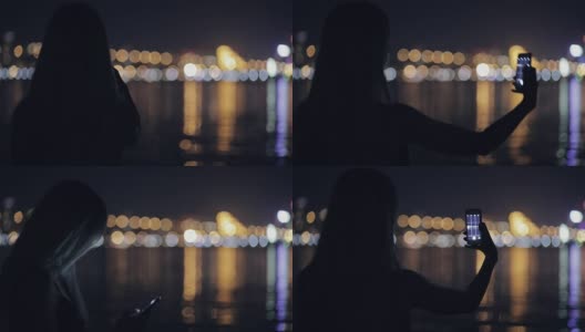 一名女子站在河边用智能手机拍摄夜景高清在线视频素材下载