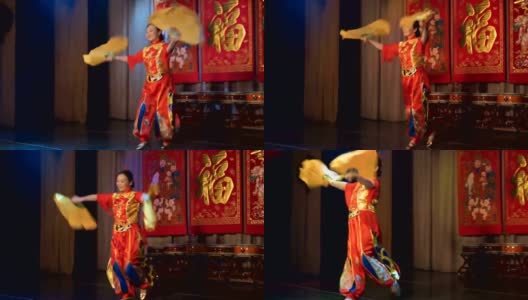 亚洲妇女穿着中国传统的红色服装，拿着大大的黄色扇子跳舞。高清在线视频素材下载