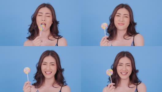 美丽的亚洲女人吃糖果与幸福的情绪在蓝色的背景。美丽，时尚和夏天的概念。高清在线视频素材下载