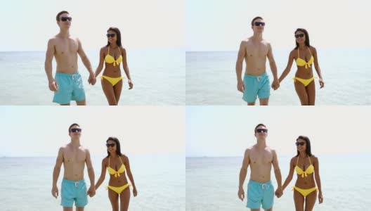 异族情侣手牵着手，在热带度假的海滩上散步高清在线视频素材下载